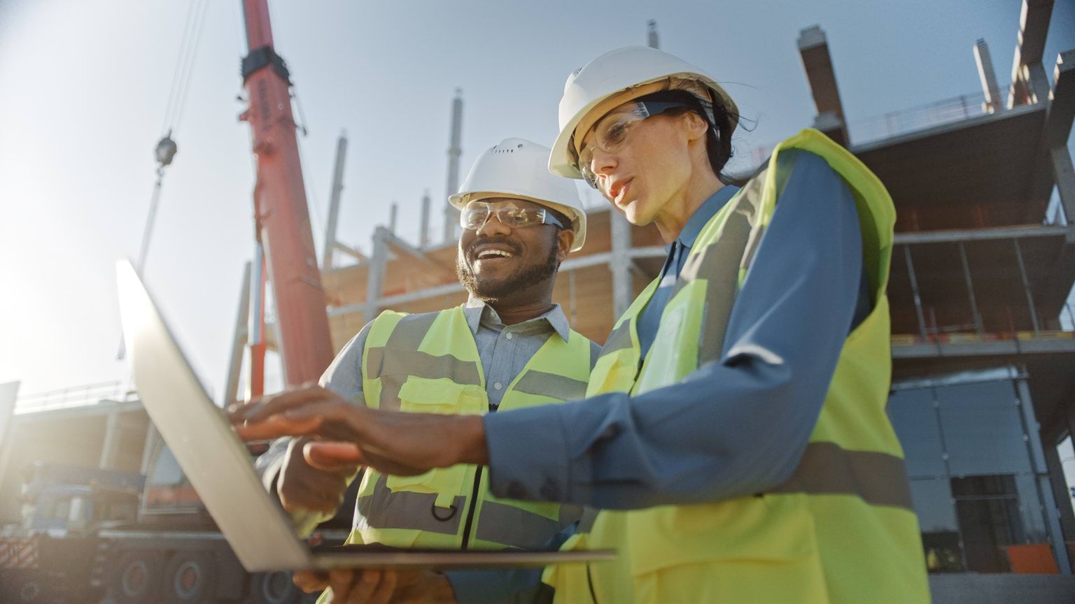 Two people in high-vis clothing looking at a laptop Two people in high-vis clothing looking at a laptop